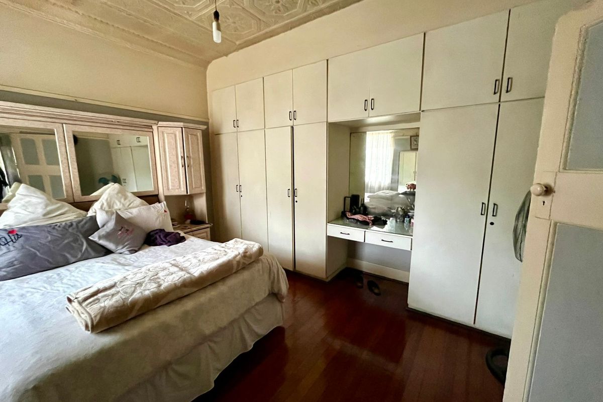 A bedroom featuring built-in floor-to-ceiling wardrobes with an integrated vanity station and decorative pressed metal ceiling detail.