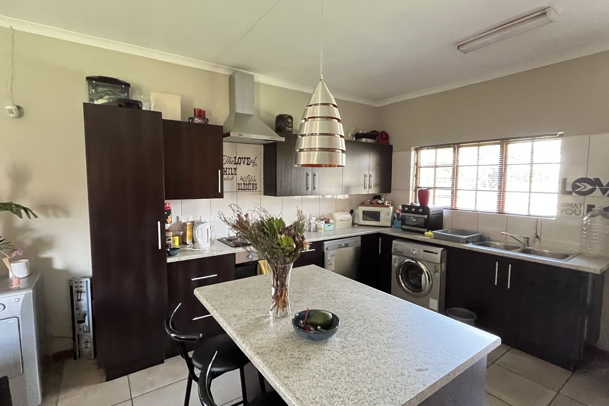 A functional kitchen featuring dark wood cabinetry, a central island with stone countertop, integrated stainless steel appliances, and tiled flooring.