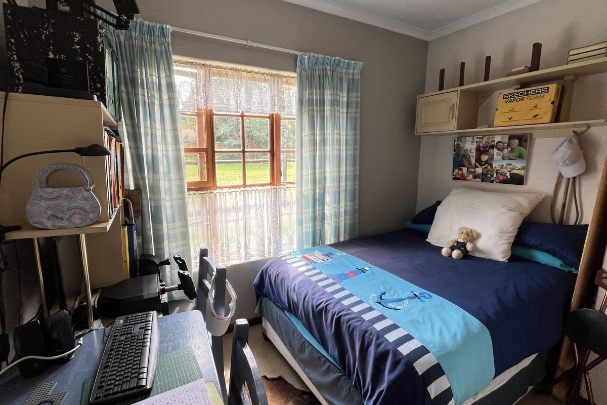 A cozy bedroom featuring built-in shelving units and a window with garden views, providing a functional and comfortable living space.