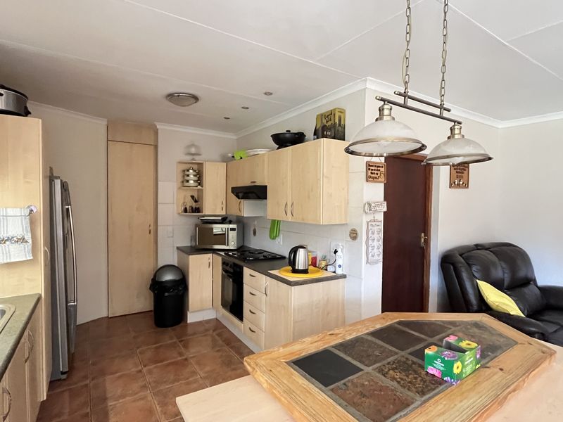 Open-plan kitchen featuring light wood cabinetry, built-in oven, hob, and extractor fan, seamlessly flowing into the adjacent living area.