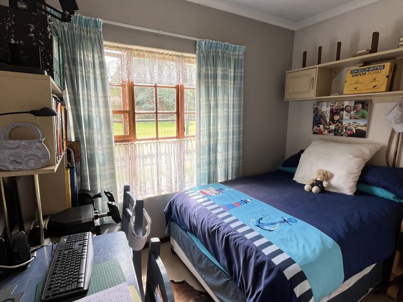 A cozy bedroom featuring built-in shelving units and a window with garden views, providing a functional and comfortable living space.