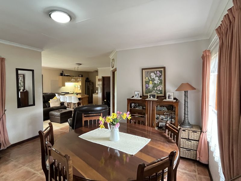 Open-plan dining and living area featuring tiled flooring, neutral walls, and a seamless flow into the adjacent kitchen space.