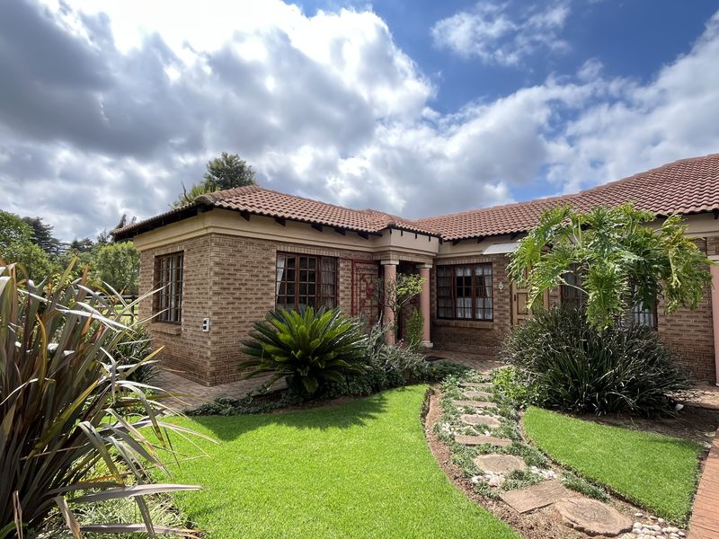 A well-maintained face-brick exterior facade featuring a tiled roof, paved driveway, and landscaped front garden with a stone pathway.