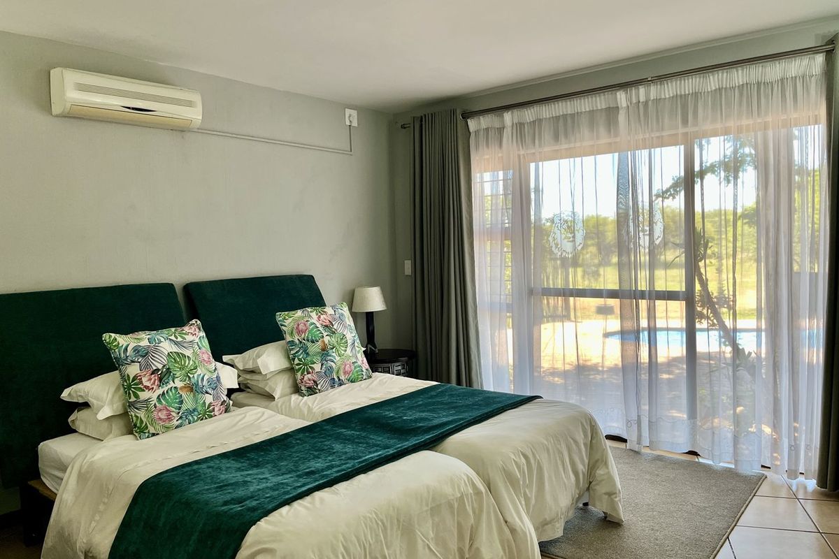 A well-maintained bedroom featuring a wall-mounted air conditioning unit and large sliding glass doors providing direct access to the pool area.