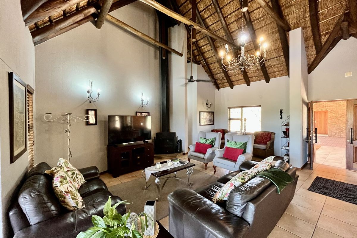 Spacious living room featuring a high vaulted thatched ceiling with exposed timber beams, a built-in fireplace, and tiled flooring.