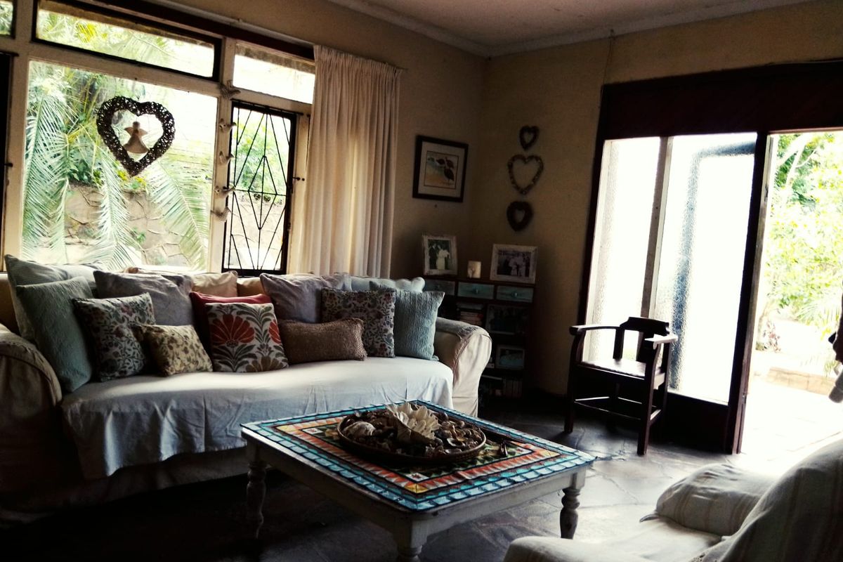A cozy living room featuring large windows, natural light, and direct access to the outdoor area through sliding glass doors.