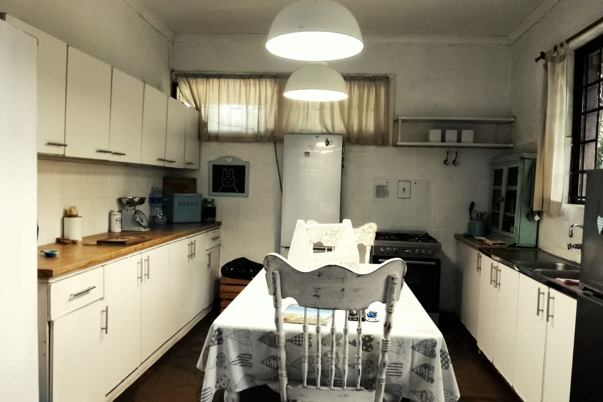 A functional kitchen featuring white cabinetry, wooden countertops, a gas stove, and a central dining area with pendant lighting.