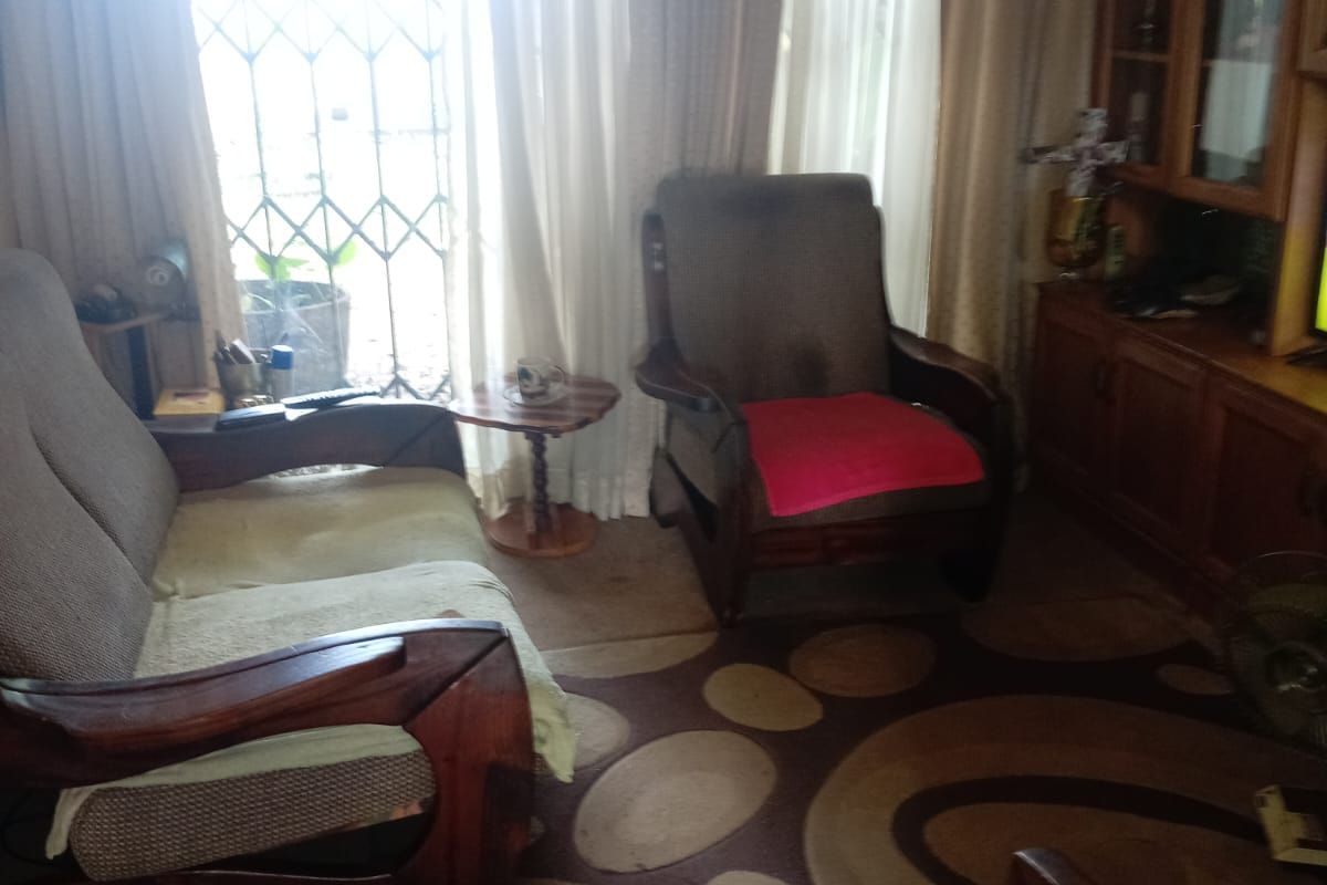 A living room area featuring a built-in wooden display cabinet and access to an exterior security gate.
