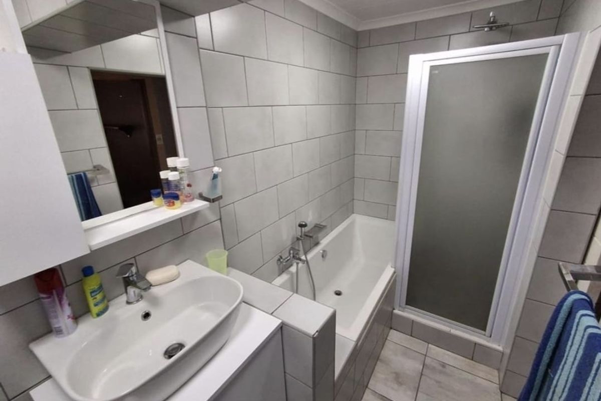 Modern bathroom featuring a vessel sink vanity, a built-in bathtub, and a separate glass-enclosed shower with grey wall tiling.