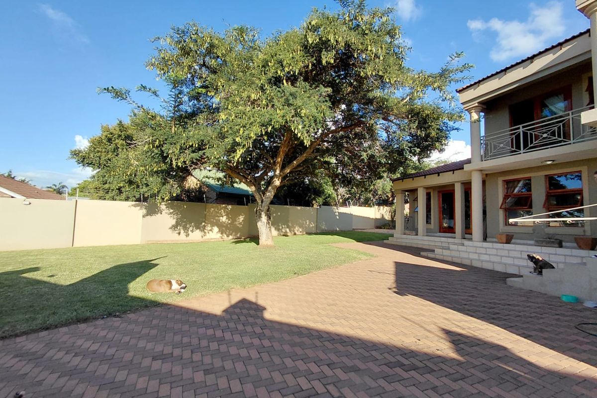 Spacious rear garden featuring a paved patio area, well-maintained lawn, and mature tree, providing a private outdoor space for relaxation and entertainment.