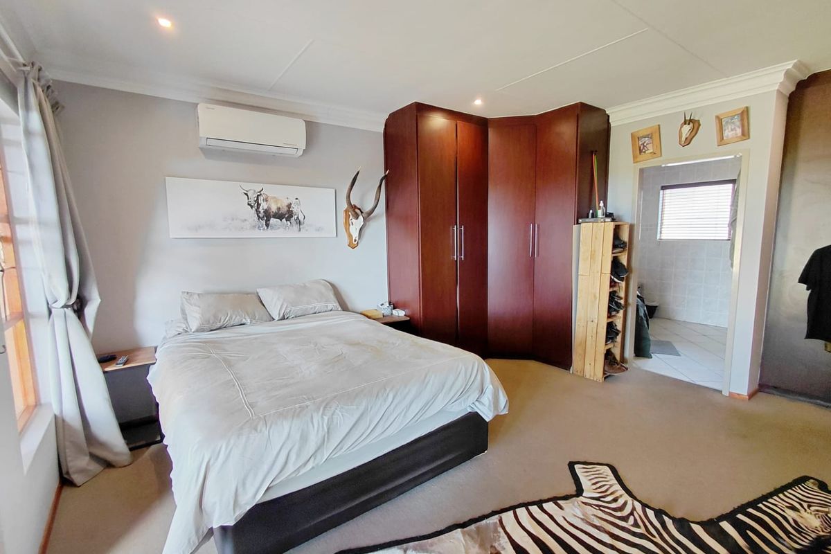 Spacious bedroom featuring built-in wooden cabinetry, an integrated air conditioning unit, and an en-suite bathroom access.