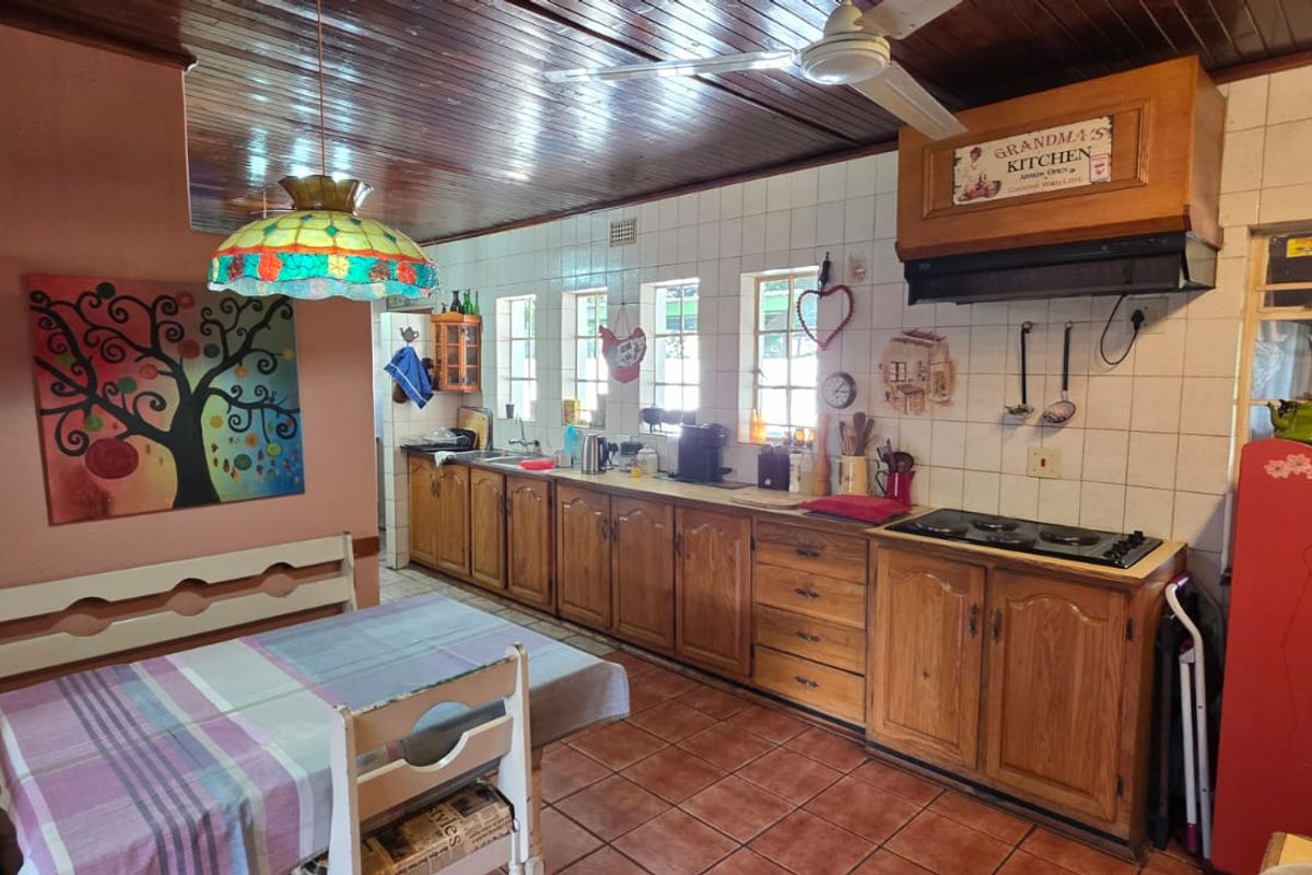A rustic kitchen featuring wooden cabinetry, tiled backsplash, built-in hob, and a timber-clad ceiling, offering a traditional and functional cooking space.