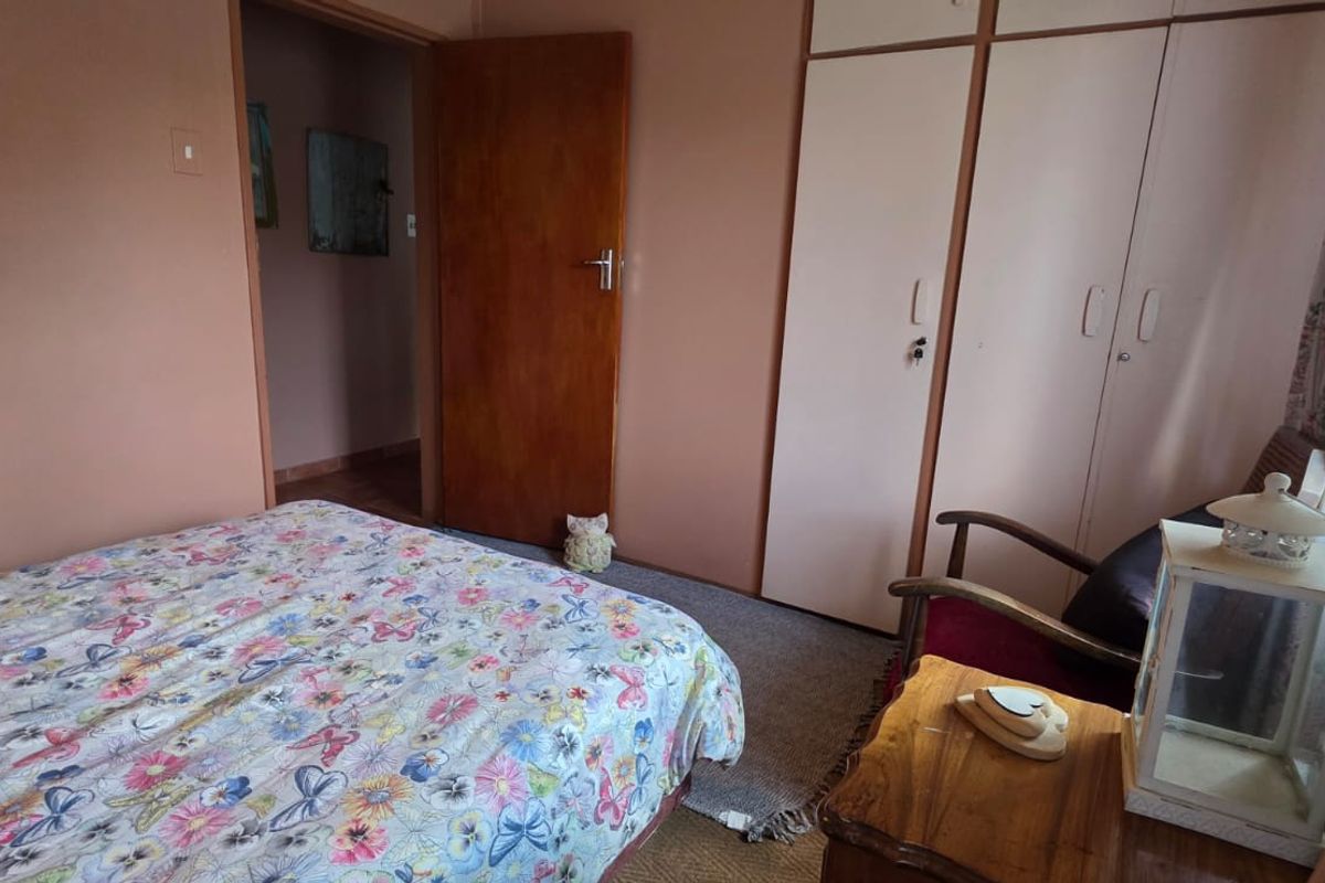A bedroom featuring built-in cupboards and a wooden door, showcasing a dated interior aesthetic ready for modernization.
