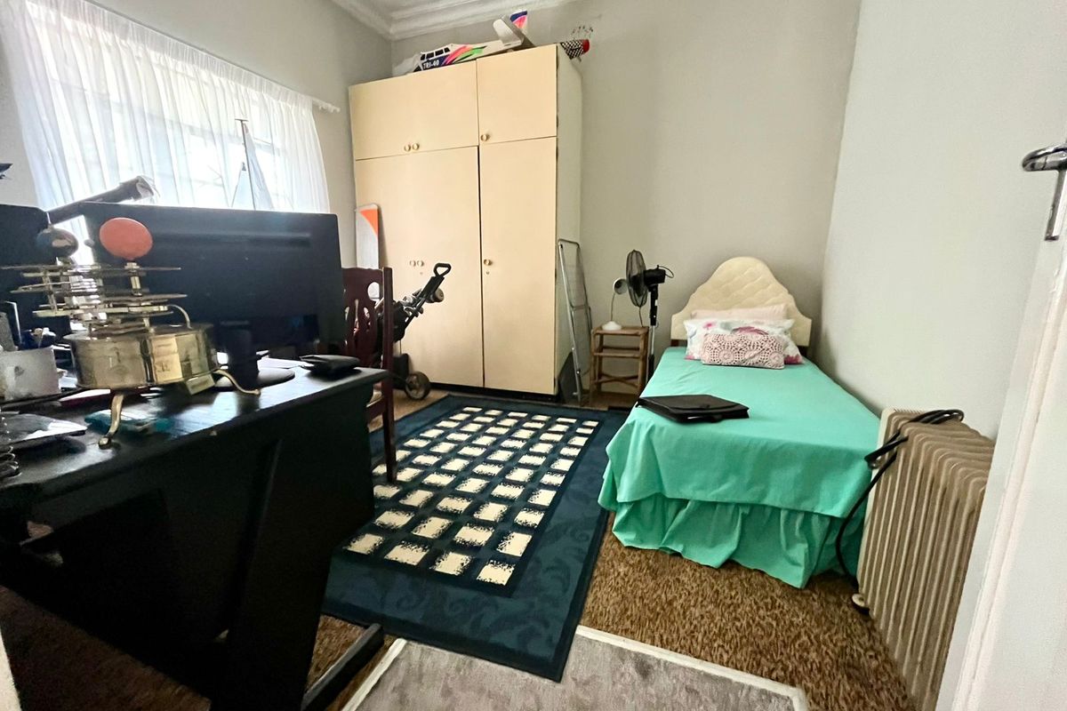 A functional bedroom featuring built-in wardrobe storage, carpeted flooring, and decorative ceiling cornice detail.
