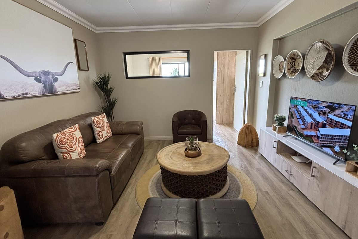 A comfortable living room featuring wood-look flooring, neutral wall tones, and a built-in media console, creating a warm and inviting atmosphere.