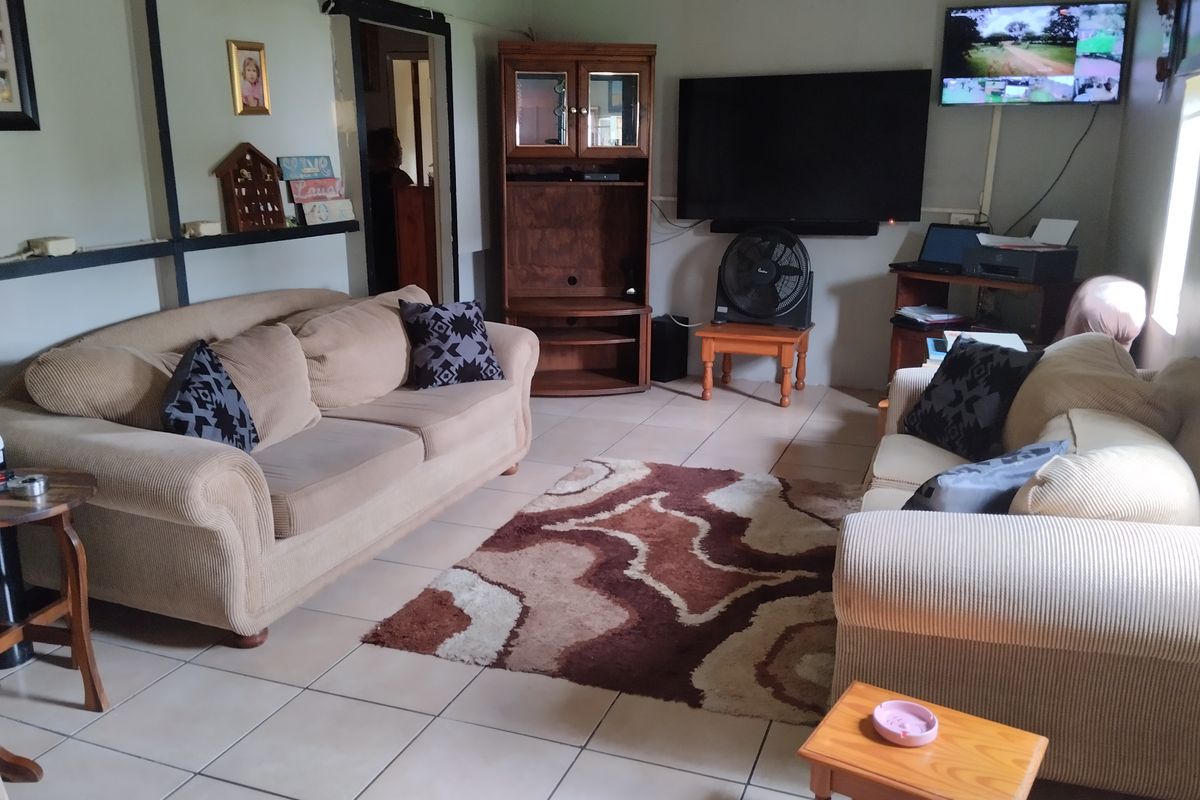 A comfortable living room featuring tiled flooring and exposed structural beams, providing a functional space for relaxation and entertainment.