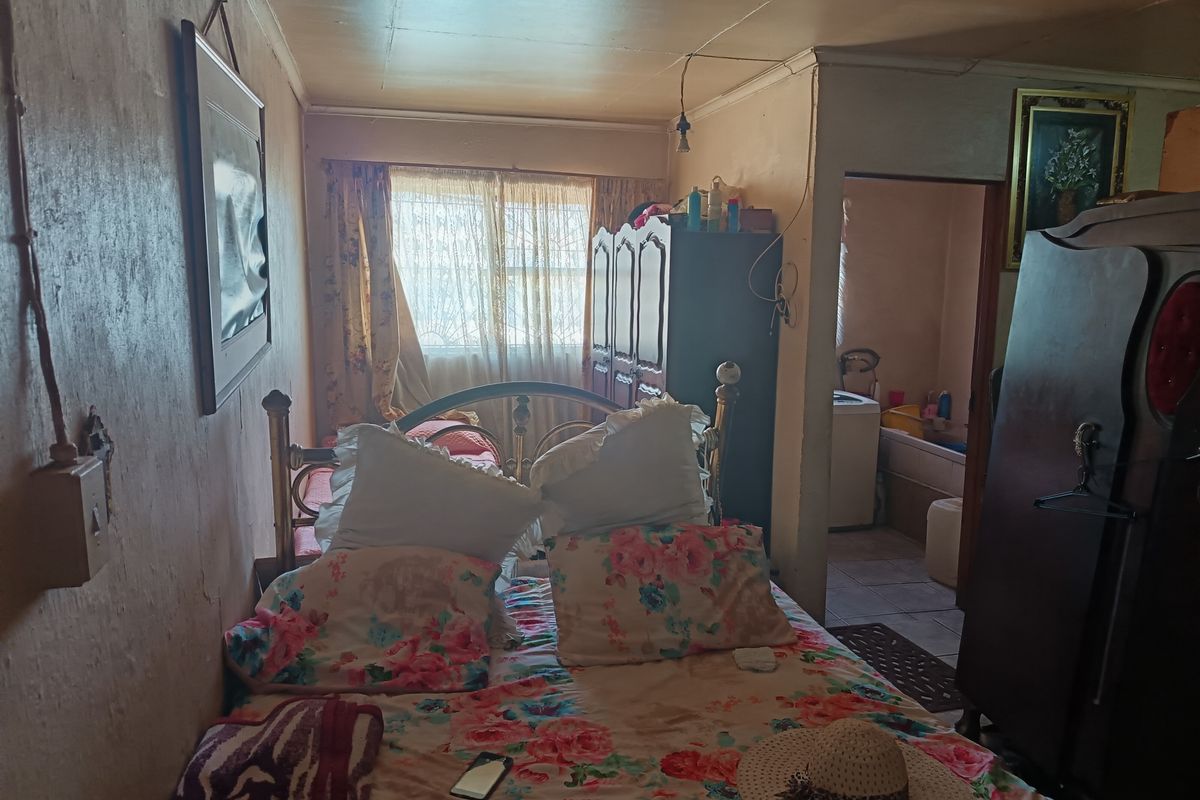 A bedroom featuring dated wall finishes and ceiling, with an adjoining bathroom area visible in the background.