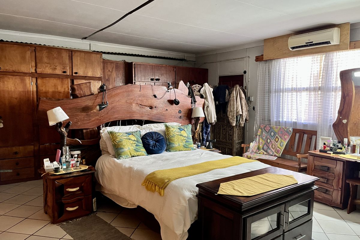 Spacious bedroom featuring extensive built-in wooden cabinetry, tiled flooring, and a wall-mounted air conditioning unit.