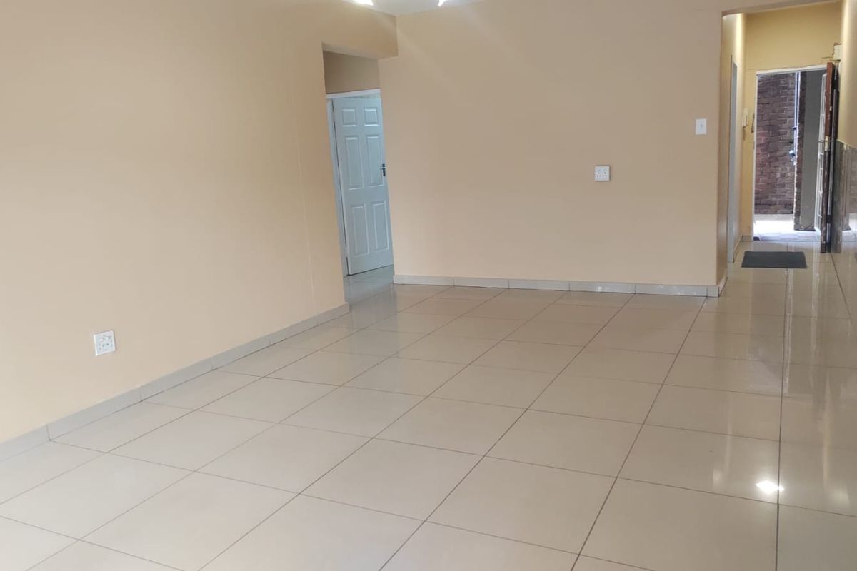 A spacious, empty living area featuring neutral wall tones and light-colored floor tiles, providing a versatile blank canvas for interior design.