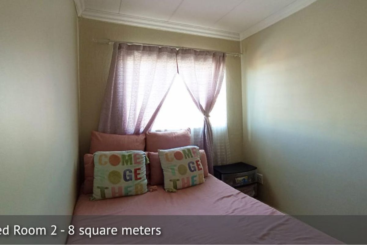 A compact bedroom featuring neutral walls, crown molding, and a window with curtain rod.