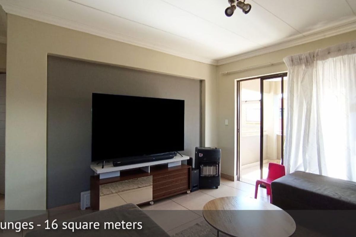 A living room featuring tiled flooring, a recessed feature wall, and sliding glass doors providing access to an outdoor balcony area.