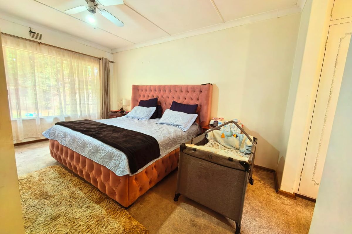 A spacious bedroom featuring built-in cupboards, a ceiling fan, and large windows that provide ample natural light.
