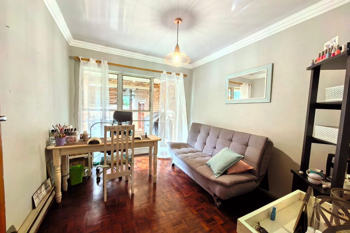 A versatile room featuring polished parquet flooring, crown molding, and a large window providing natural light, suitable for use as a home office or bedroom.