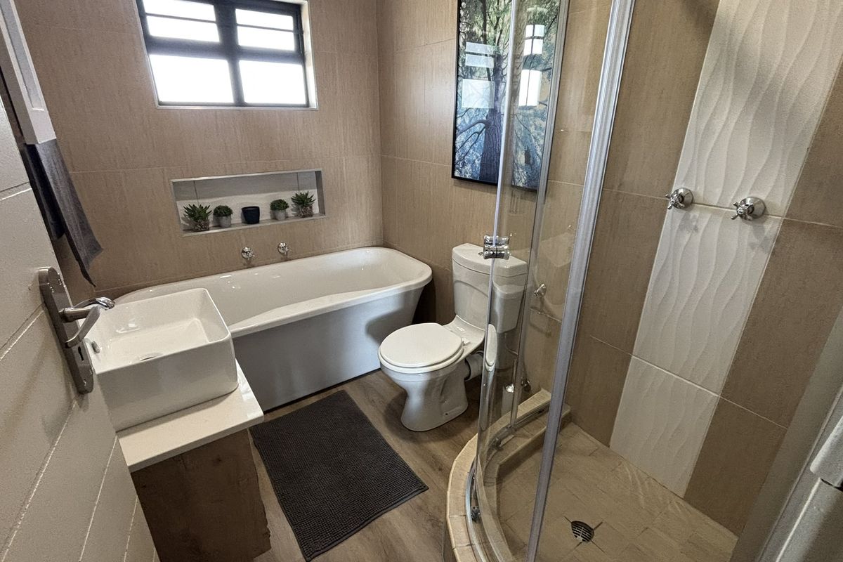 Modern bathroom featuring a separate glass-enclosed shower, a freestanding bathtub, a vessel sink vanity, and neutral wall tiling.