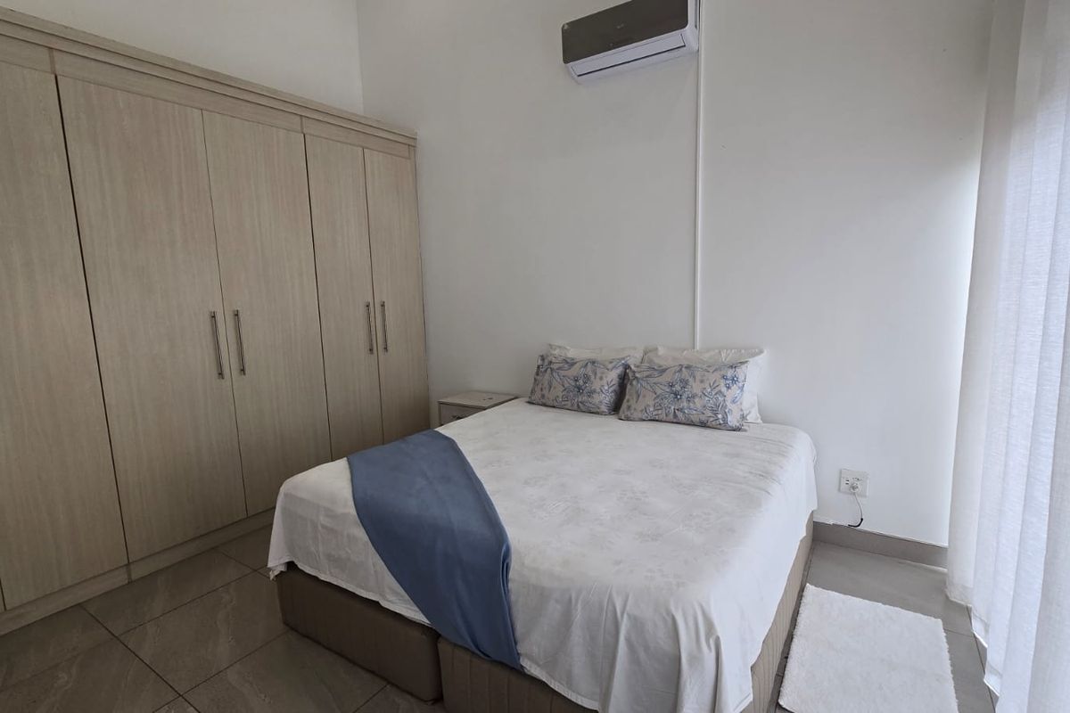 A well-maintained bedroom featuring built-in wooden cabinetry, tiled flooring, and a wall-mounted air conditioning unit.