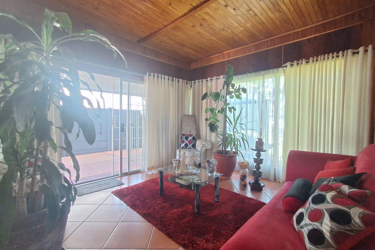 Living room featuring a warm timber-clad ceiling, tiled flooring, and large sliding glass doors providing access to the outdoor area.