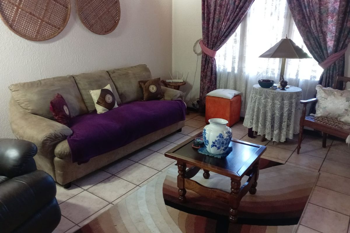 A comfortable living room featuring ceramic floor tiles and large windows with curtains, providing a bright and functional space for relaxation.