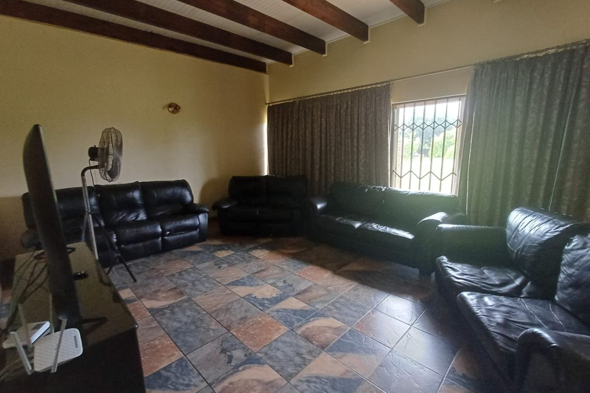 Spacious living room featuring exposed timber ceiling beams and tiled flooring, offering a comfortable area for relaxation and family gatherings.