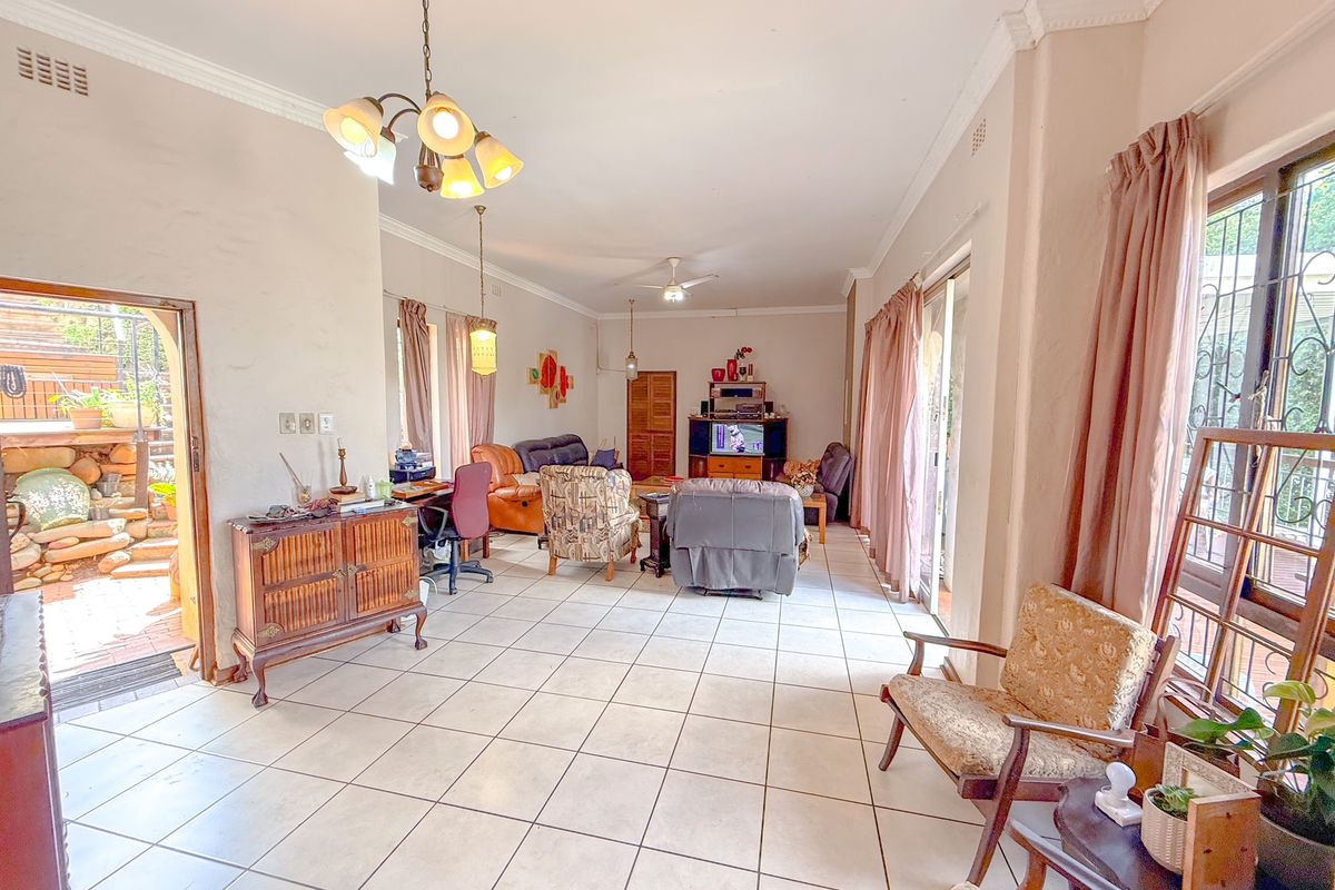 Spacious living area featuring tiled flooring, crown molding, and large sliding glass doors providing access to the outdoor patio area.