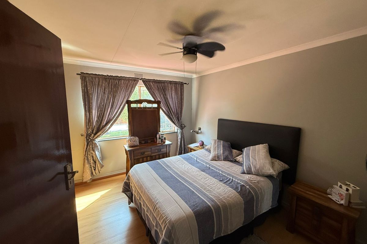 A bedroom featuring laminate flooring, a ceiling fan, and coving, providing a functional and comfortable sleeping space.
