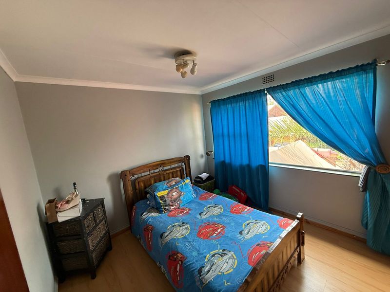 A standard bedroom featuring laminate flooring, a ceiling light fixture, and a ventilation grille, providing a functional space for rest.