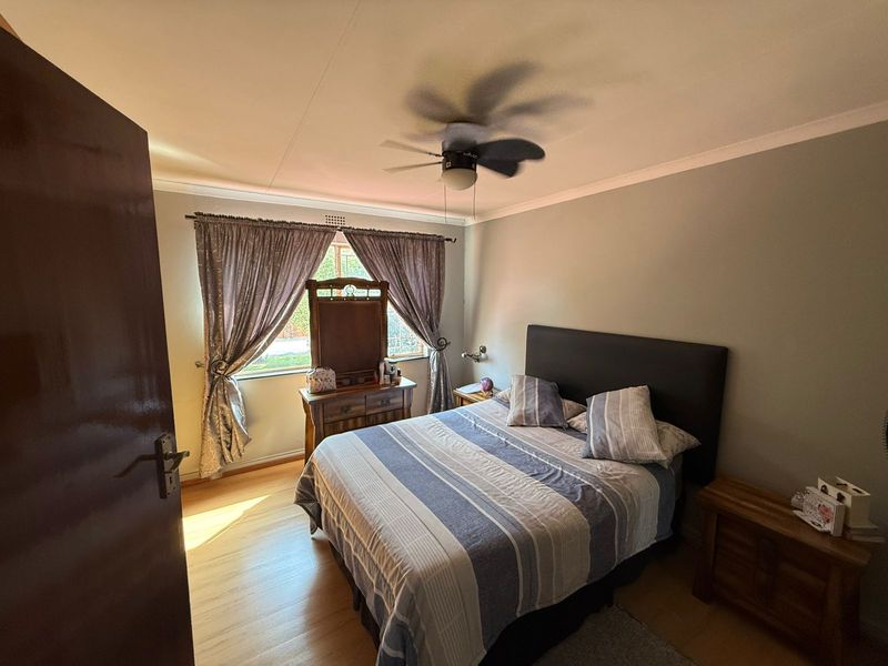 A bedroom featuring laminate flooring, a ceiling fan, and coving, providing a functional and comfortable sleeping space.
