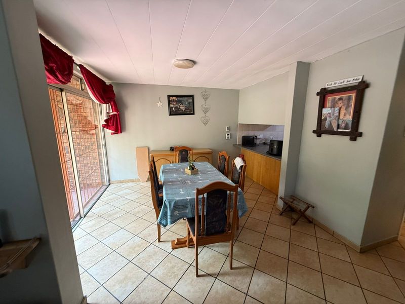 Open plan dining area featuring tiled flooring and a sliding glass door leading to the exterior, adjacent to a compact kitchen space.