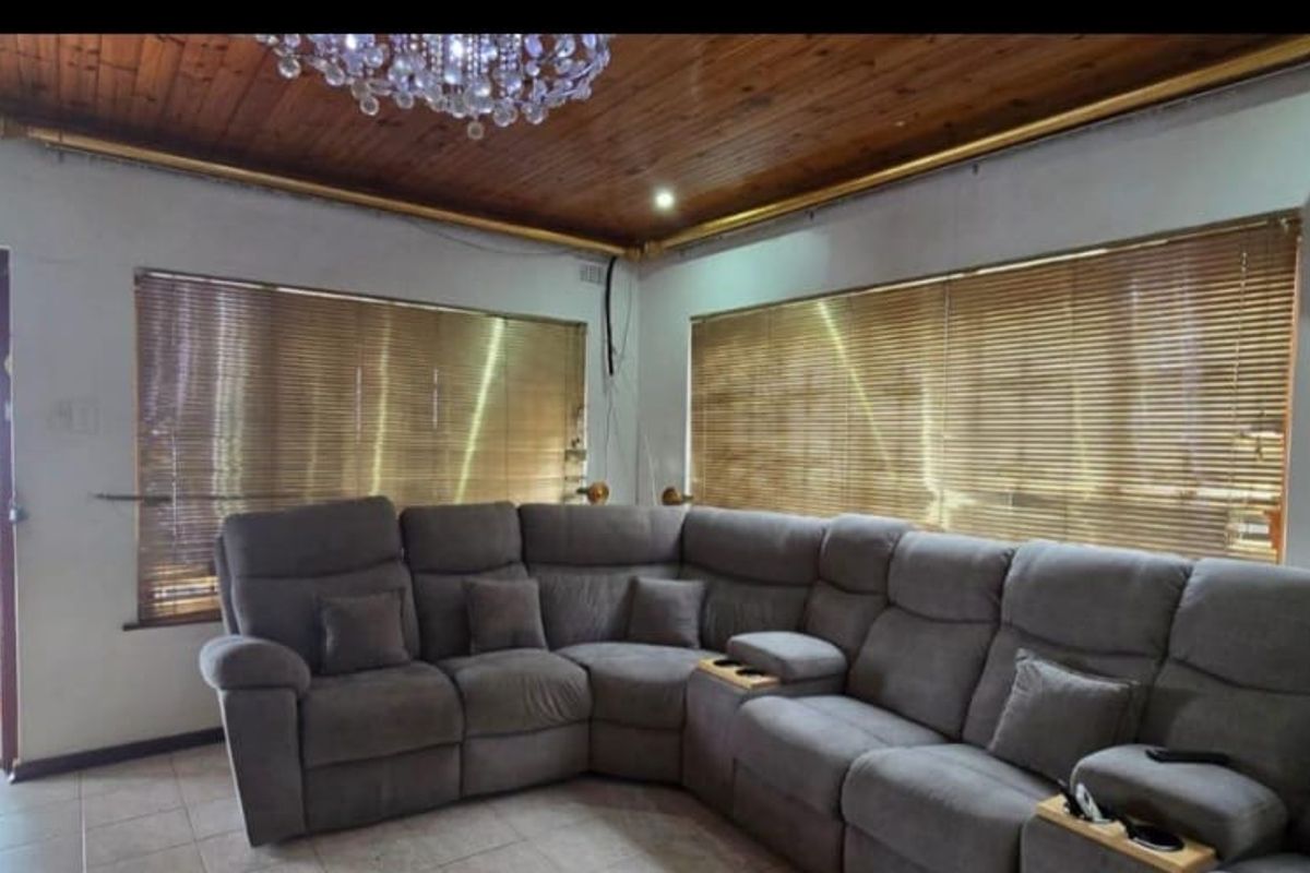 A living room featuring a timber-clad ceiling, tiled flooring, venetian blinds, and a wall-mounted air conditioning unit, with direct access to an outdoor patio.