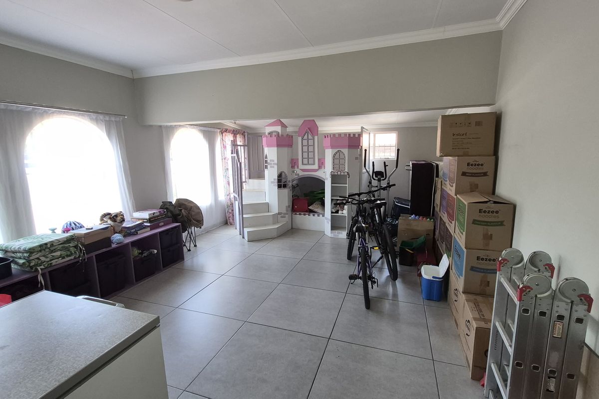 Spacious living area featuring large arched windows, tiled flooring, and neutral wall finishes, offering a versatile layout for various living arrangements.