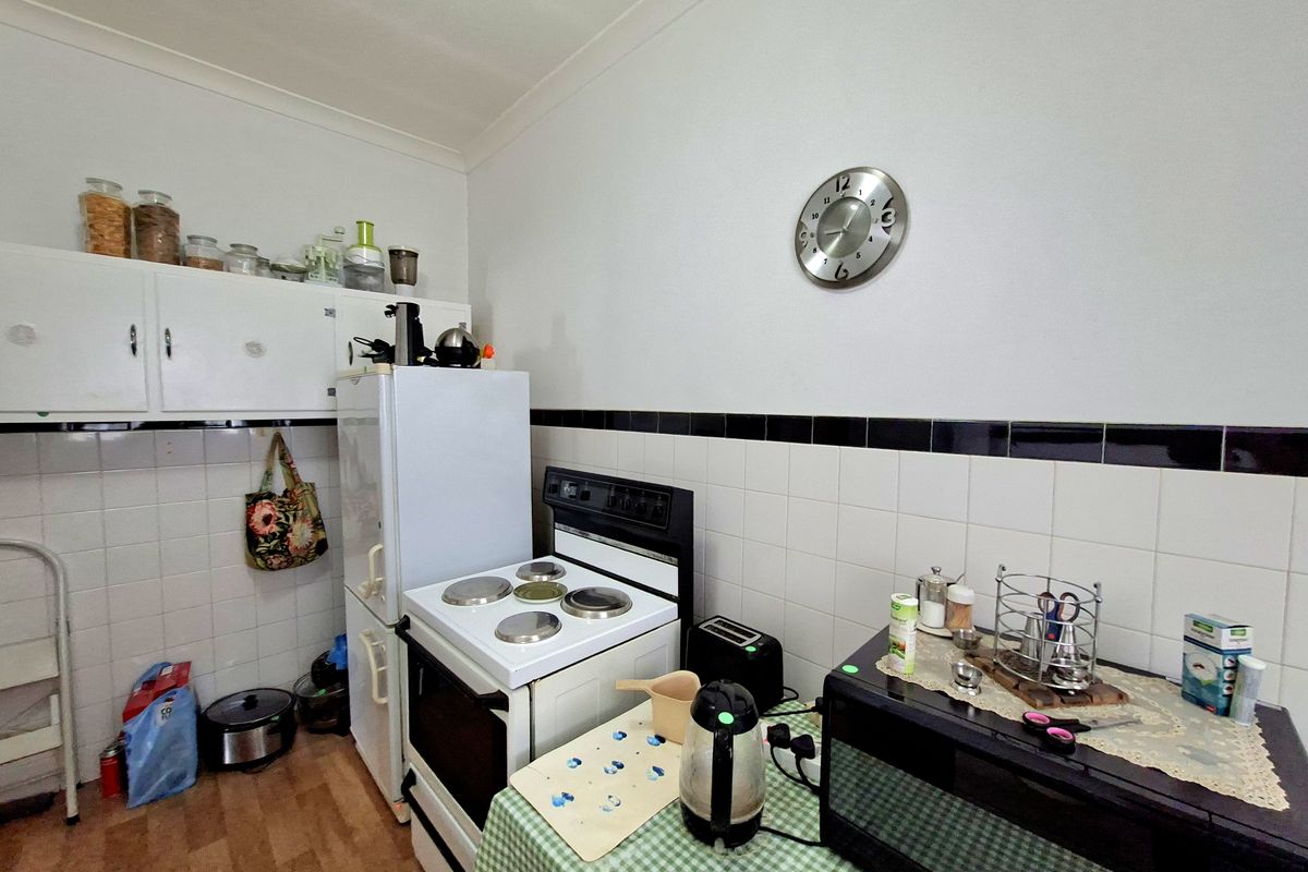 A functional kitchen featuring white cabinetry, a tiled splashback with a black accent border, and a freestanding electric stove.