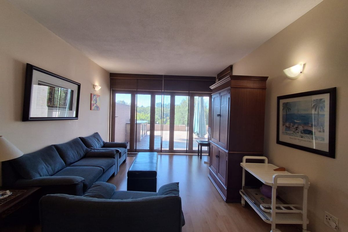 A comfortable living room featuring laminate flooring and large sliding glass doors that provide direct access to an outdoor patio area.