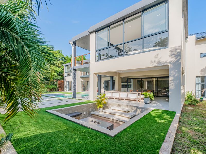 Modern rear exterior featuring a sunken fire pit, swimming pool, covered patio, and expansive glass sliding doors opening to the living area.