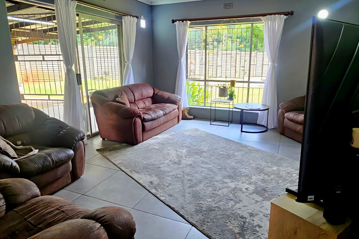 A comfortable living room featuring large windows, tiled flooring, and sliding glass doors that provide access to the outdoor area.