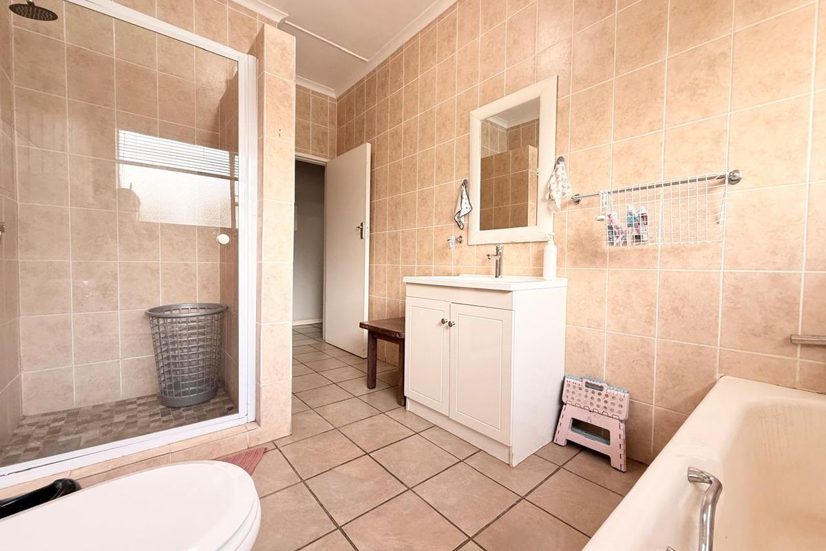 A functional bathroom featuring a glass-enclosed shower, a separate bathtub, and a vanity cabinet with a basin.