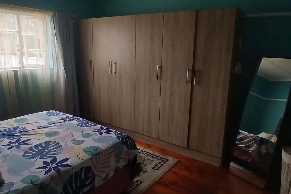 A bedroom featuring built-in wooden cabinetry and polished timber flooring, providing ample storage space and a warm aesthetic.