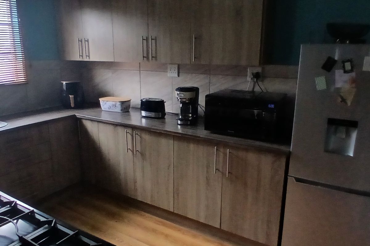 A functional kitchen featuring wood-look cabinetry, laminate countertops, and a built-in gas hob, providing a practical workspace with ample storage.