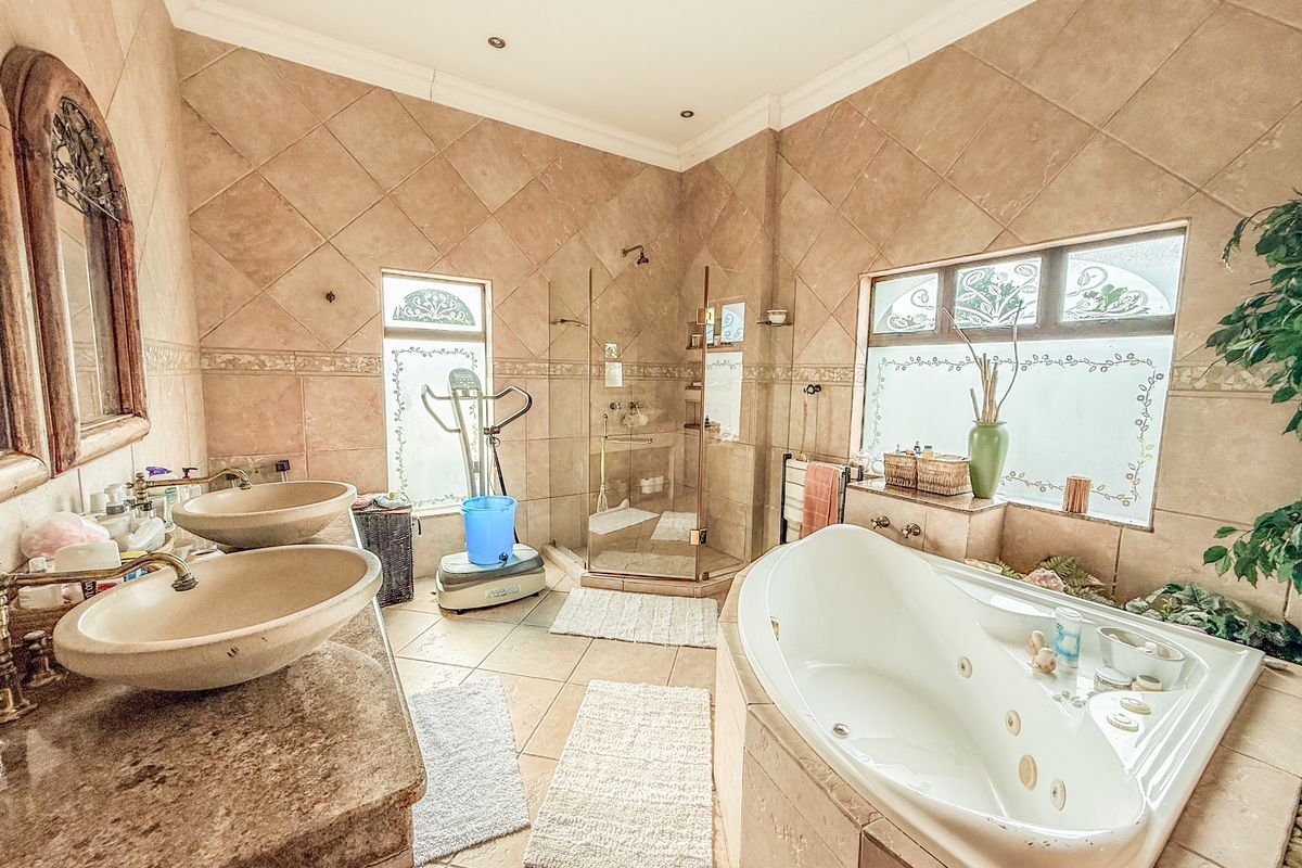 Spacious bathroom featuring a corner jetted tub, glass-enclosed shower, and dual stone vessel sinks set on a granite vanity top.
