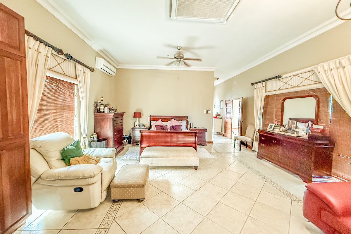 Spacious bedroom featuring tiled flooring, a ceiling fan, and a wall-mounted air conditioning unit.