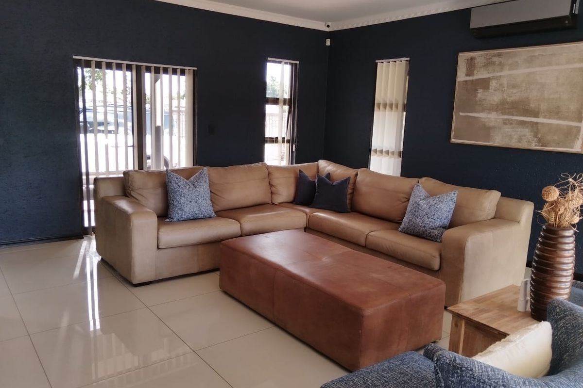 Spacious living room featuring dark accent walls, polished tile flooring, and a wall-mounted air conditioning unit.