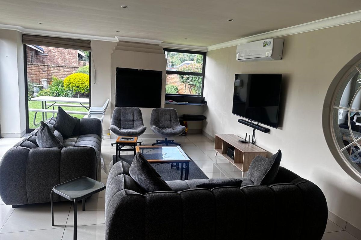Spacious living room featuring large windows, tiled flooring, recessed lighting, and a wall-mounted air conditioning unit, with direct access to the garden area.